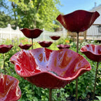 Red glass flower-shaped bird baths in a garden setting