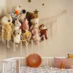 Children's room with stuffed animals on a macrame wall hanging above a crib.