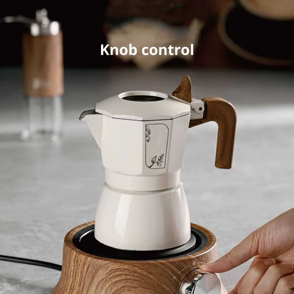 White espresso maker with wooden handle and base, being controlled by a hand on a blurred kitchen background.