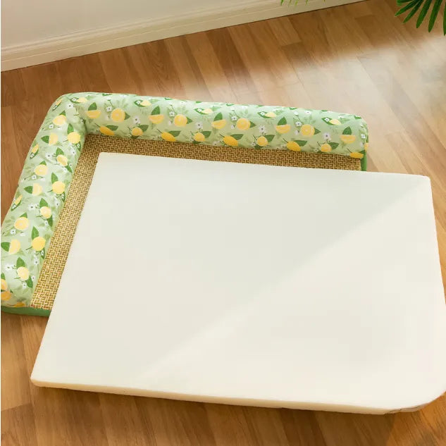 White foam mattress topper on a wooden floor with a decorative green border featuring lemon pattern.