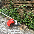 Gardening tool being used to trim plants against a brick wall.