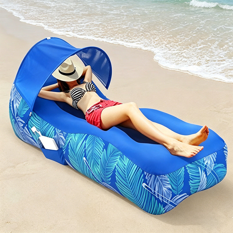 Person lounging on a blue inflatable beach lounger with canopy at the beach.