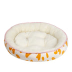 Round pet bed with white interior, pink rim, and orange paw print pattern on a white background