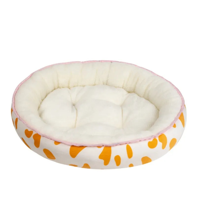Round pet bed with white interior, pink rim, and orange paw print pattern on a white background