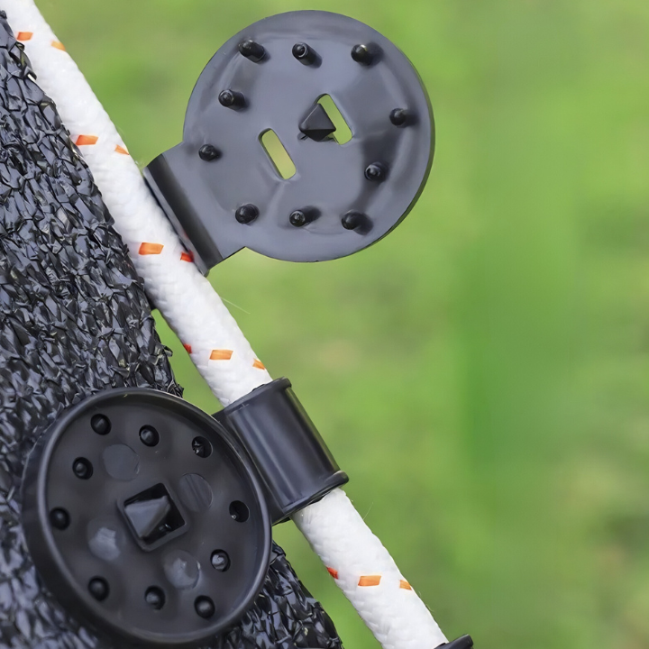 Close-up of a black metal clip attached to a white rope with orange accents, against a blurred green background.