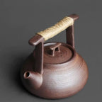 Brown ceramic teapot with a rope handle on a dark background
