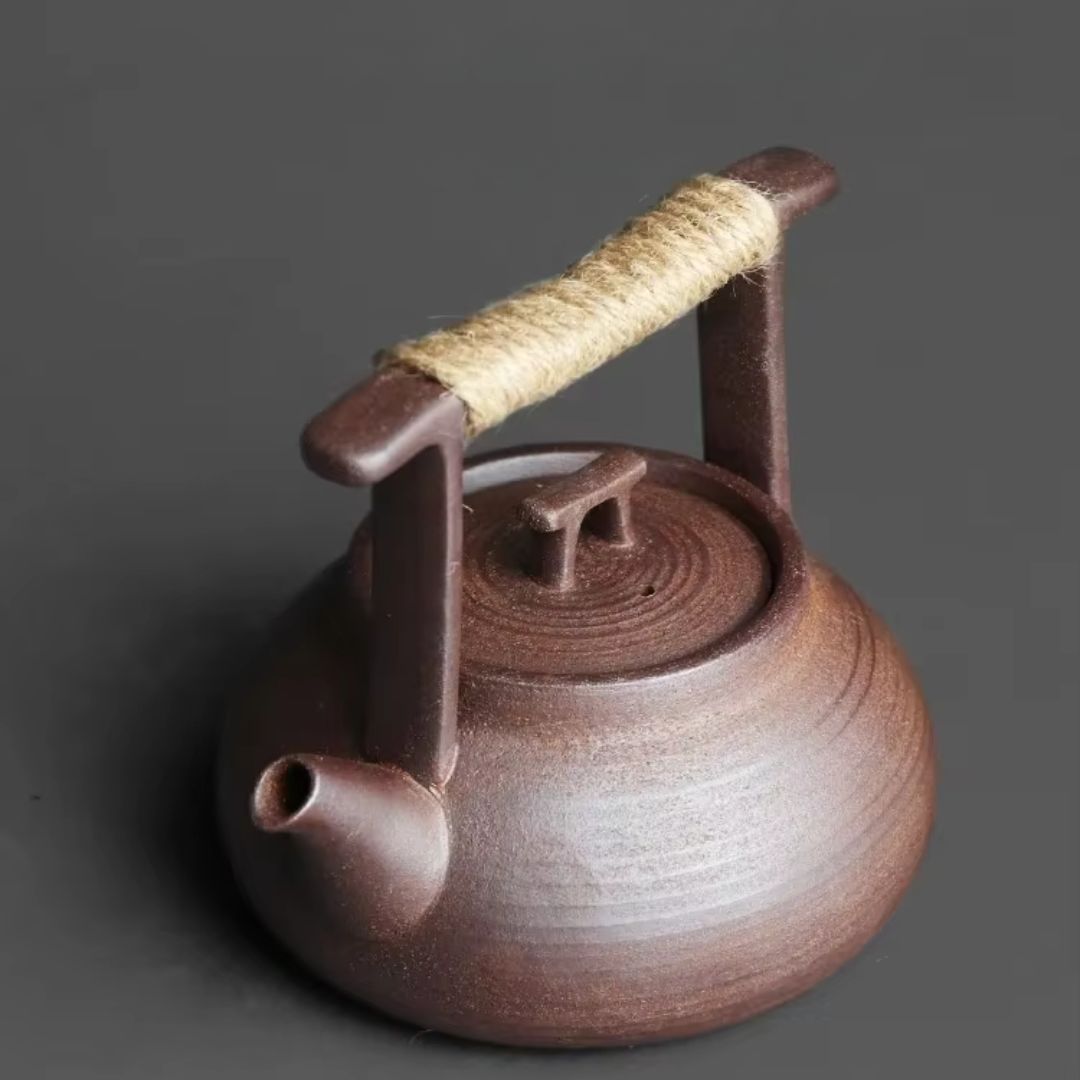 Brown ceramic teapot with a rope handle on a dark background
