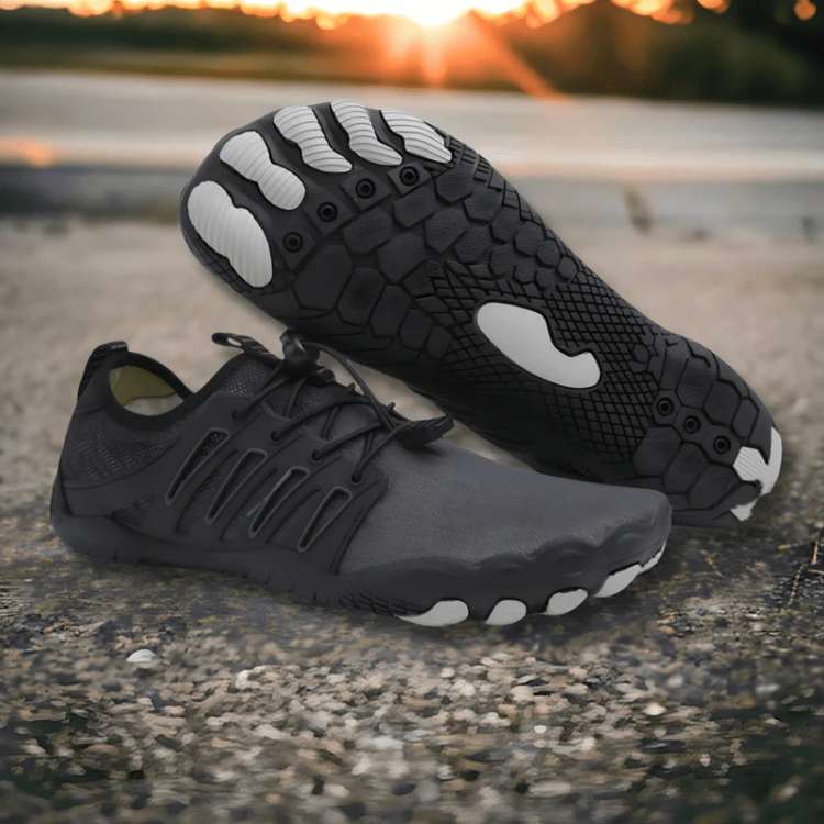 Black and gray athletic shoes with unique sole design on a concrete surface.