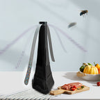 Black fly swatter on a kitchen counter with food and a fly in the background