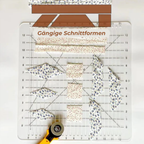 Quilting ruler with patterned fabric pieces and a rotary cutter on a white background