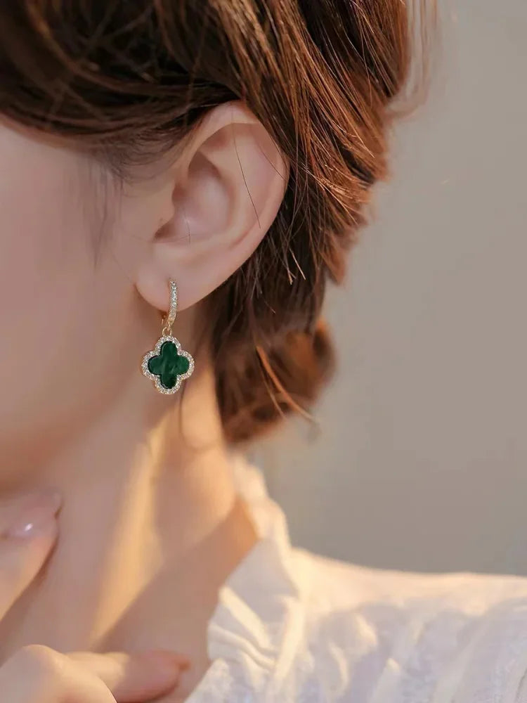 Close-up of a person wearing a green emerald earring with a blurred background