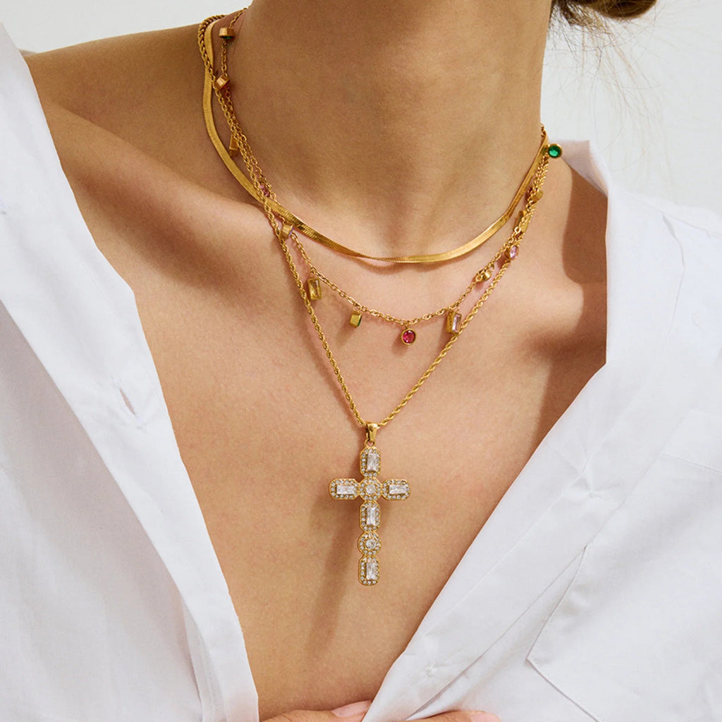Gold necklace with a cross pendant worn by a person against a white background