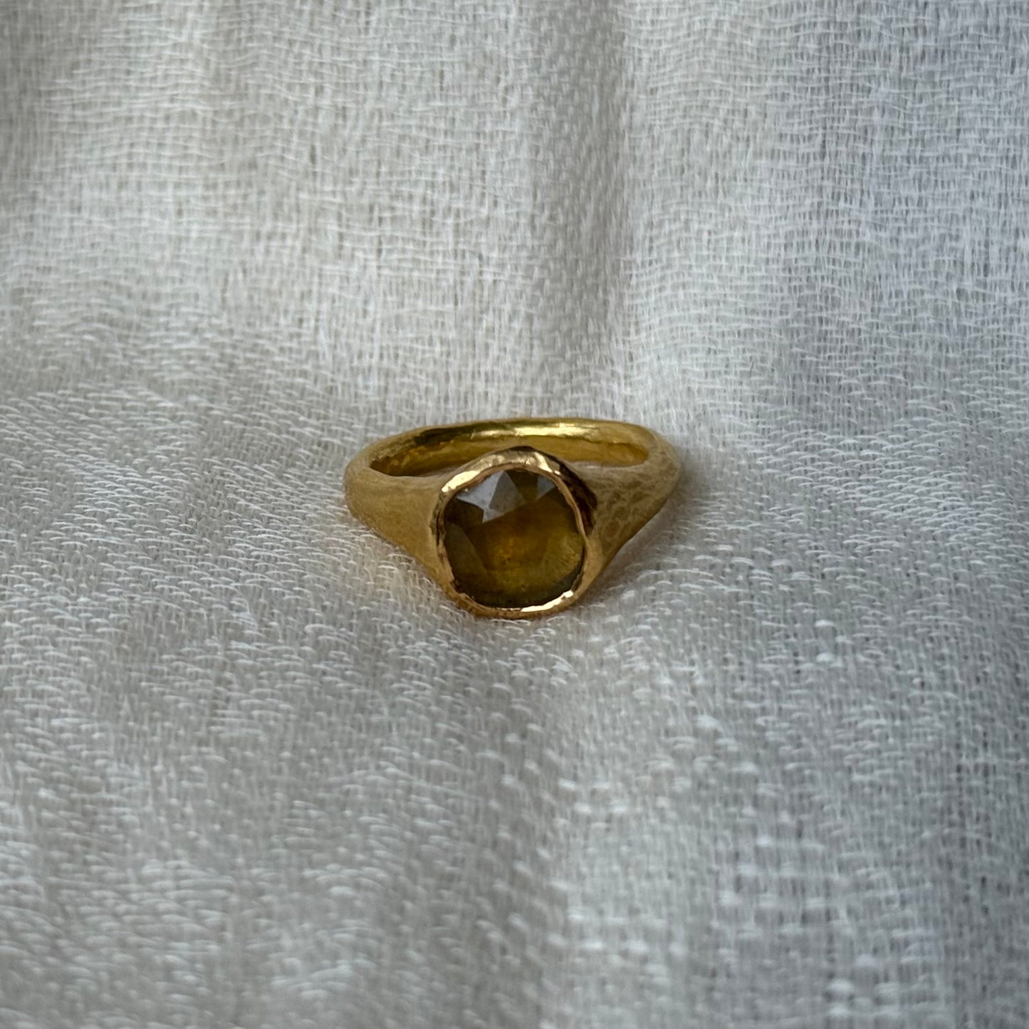 22ct Gold ring with a central yellow sapphire stone on a textured gray background