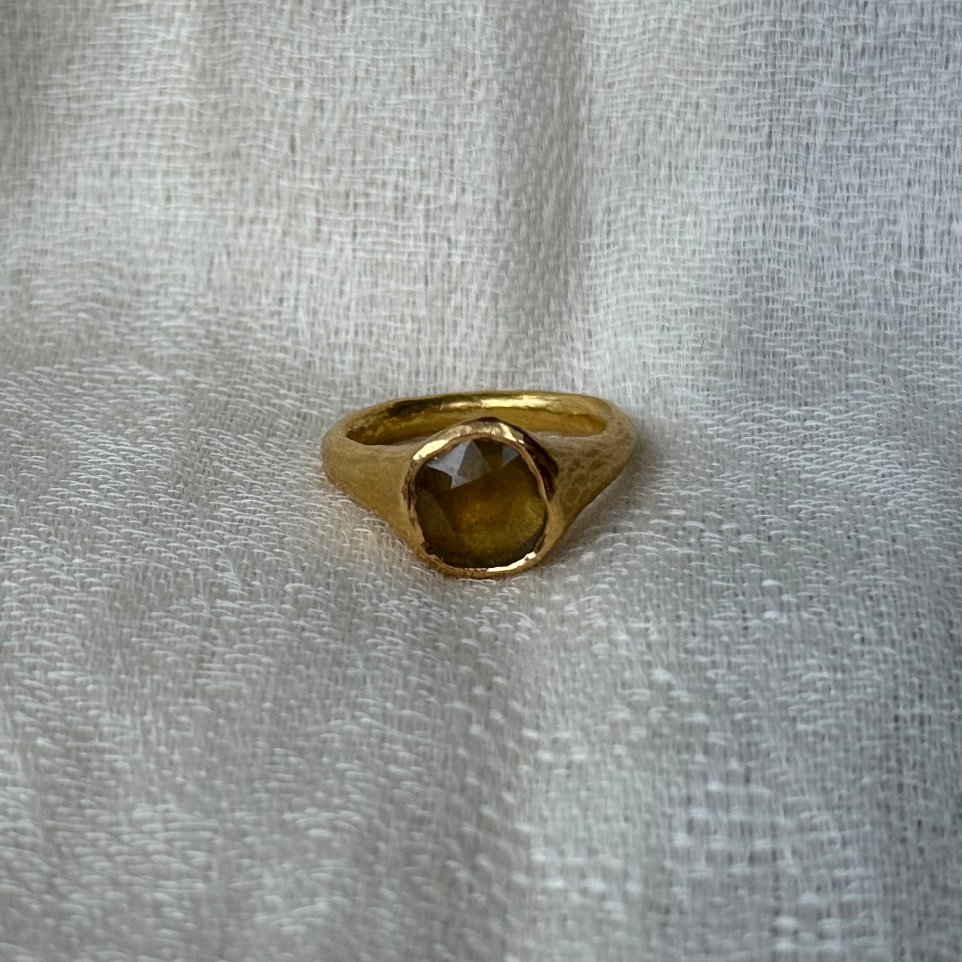 22ct Gold ring with a central yellow sapphire stone on a textured gray background