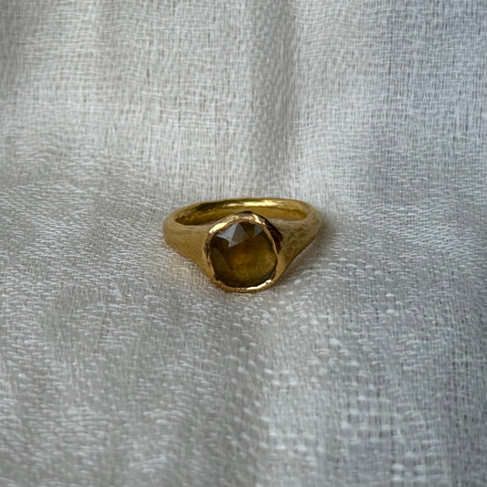 22ct Gold ring with a central yellow sapphire stone on a textured gray background