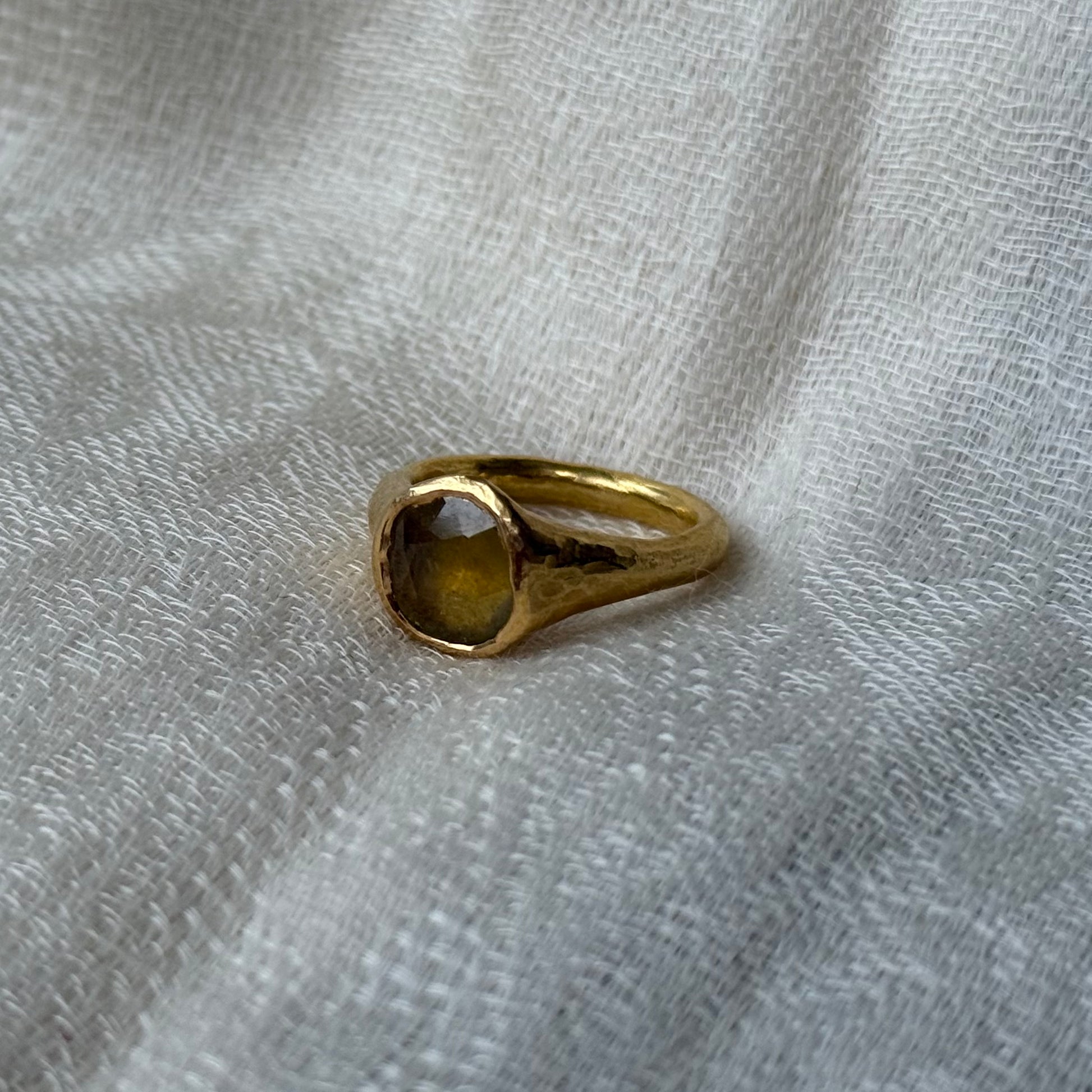 22ct Gold ring with a yellow sapphire gemstone on a textured gray fabric background
